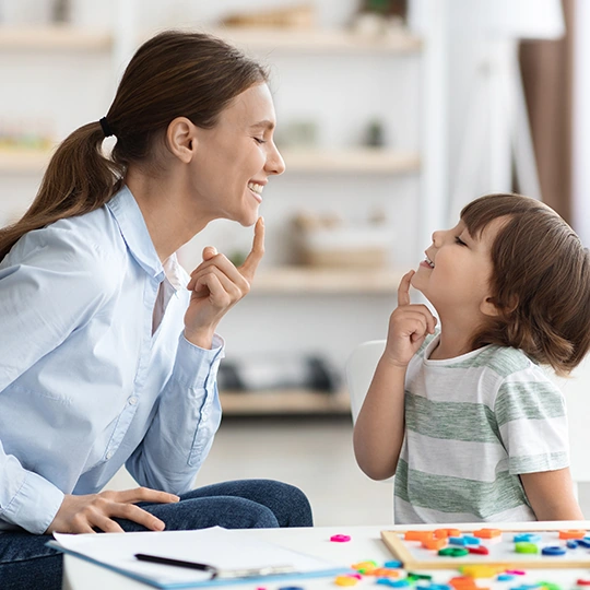 A therapist working with a young boy on speech sounds